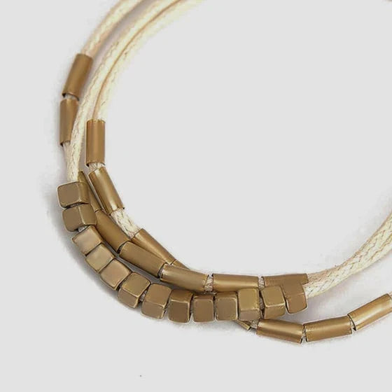Elegant layered bracelet with beige leather and gold-coloured beads, a versatile accessory for modern British style