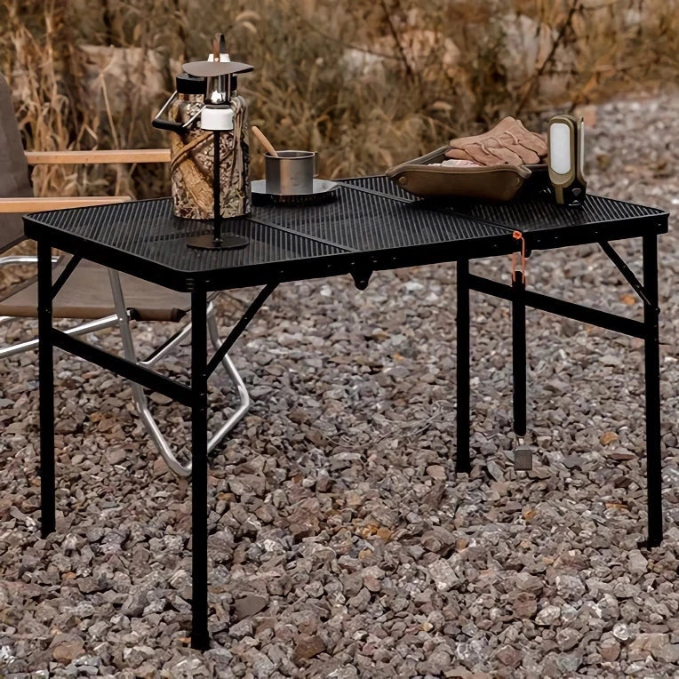 Adjustable portable folding camping table with aluminium frame, black in colour, set up outdoors