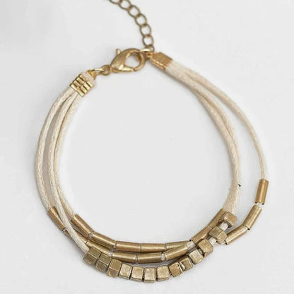 Elegant layered bracelet with beige leather and gold-coloured beads, a versatile accessory for modern British style