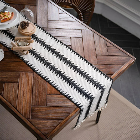 Elegant black and white cotton table runner with classic striped pattern and tassels, perfect for sophisticated dining decor