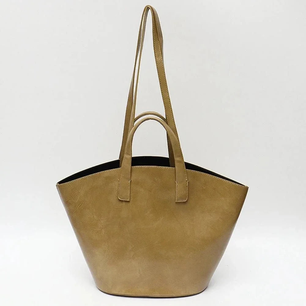 Elegant vegan leather tote bag with a unique bucket shape, short handles, and long straps for versatile carrying options