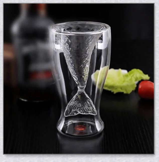 A transparent glass mug with a decorative mermaid tail design, perfect for enjoying a range of beverages in style.
