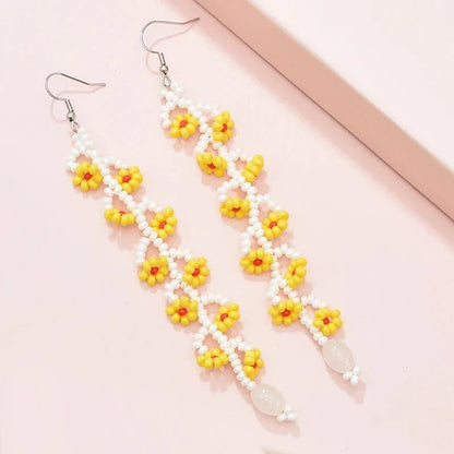 Elegant bohemian resin long tassel drop earrings in a vibrant yellow colour, featuring a mesmerising floral pattern and graceful movement