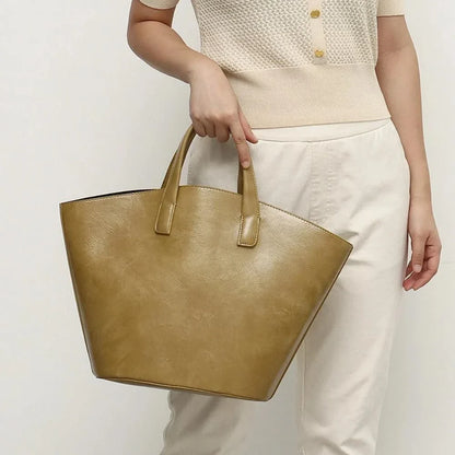 Elegant vegan leather tote bag with a unique bucket shape, short handles, and long straps for versatile carrying options