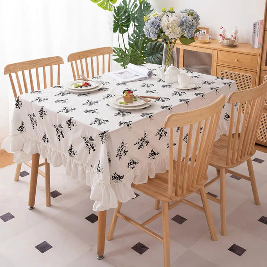 A high-quality cotton tablecloth with elegant floral embroidery and ruffled edges, creating a refined and charming dining experience.