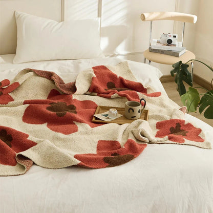 Cosy floral knitted throw blanket in red, grey, and orange shades - a high-quality microfibre accessory for year-round comfort and style