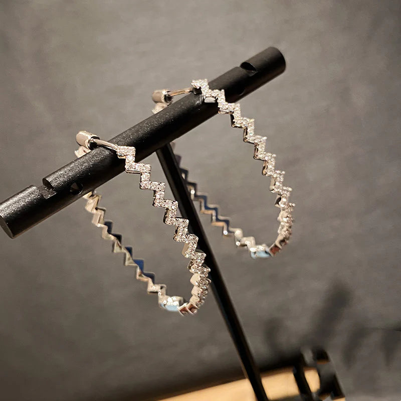 A pair of elegant sterling silver geometric earrings with a captivating wave-like pattern, inspired by the latest fashion trends in Japan and South Korea.