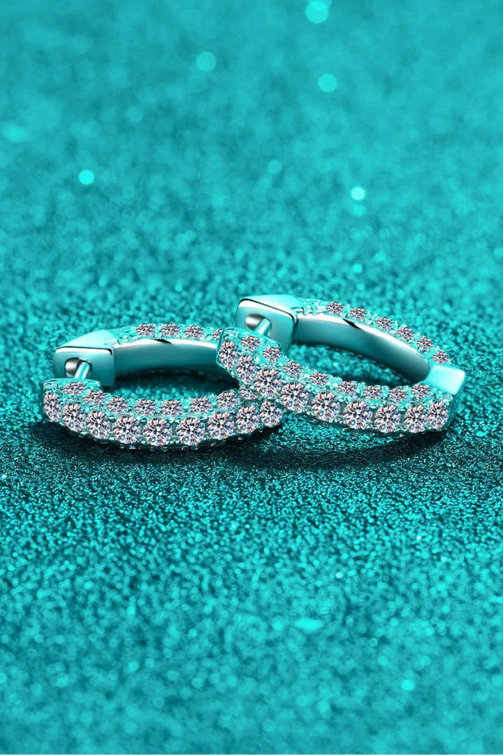 Pair of elegant sterling silver huggie earrings adorned with dazzling moissanite stones, showcasing a minimalist and sophisticated design.