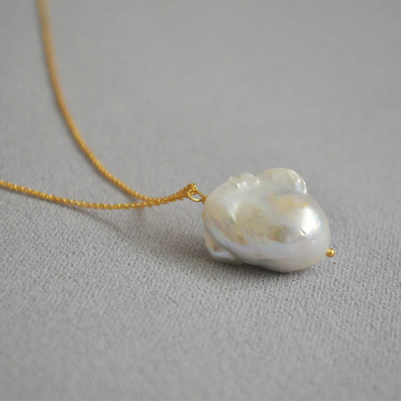 Elegant freshwater pearl necklace with a unique fish tail-shaped pendant and a delicate O-shaped chain