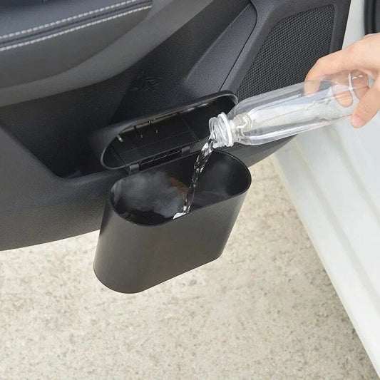 A compact black car bin with a press-type lid, designed to hang on the door panel and store garbage securely