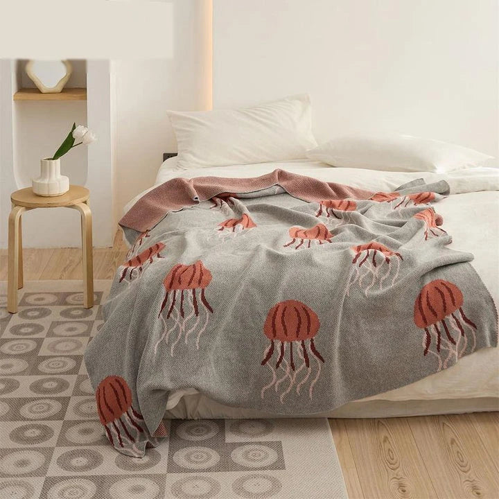 Cosy jellyfish-patterned cotton knit throw blanket in green and grey colours, showcasing its soft, plush texture and unique design.