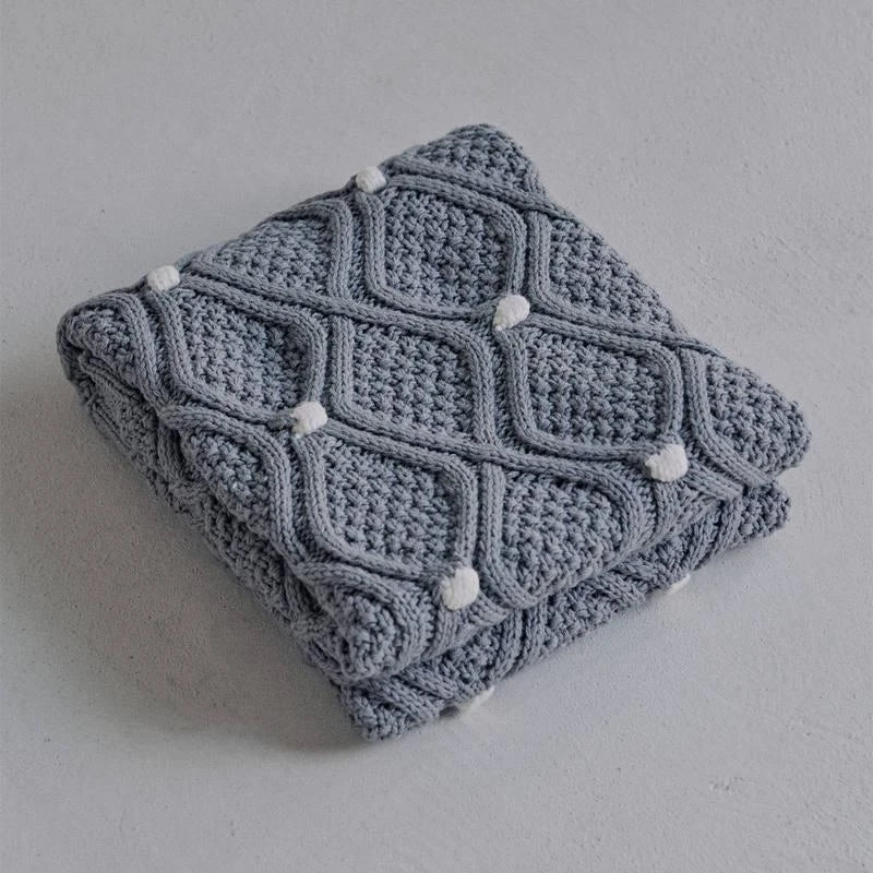 Cosy chunky knit blanket with charming pompoms in multiple sizes and colours for elegant home décor