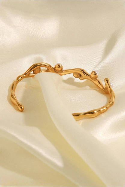 Elegant 18k gold-plated bracelet with shimmering synthetic pearls, showcasing a sleek, open design for a comfortable and stylish fit.